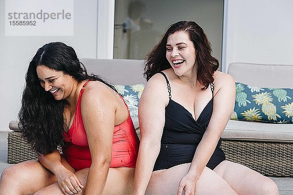 Zwei mittelgroße erwachsene Frauen sitzen zusammen lachend am Freibad  Kapstadt  Südafrika