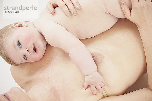 Nacktes Baby auf der nackten Mutter liegend