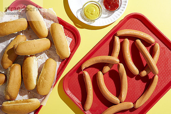 Tablett mit Fingerbrot und Tablett mit Hotdogs auf gelbem Hintergrund