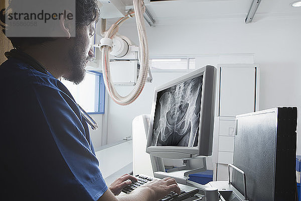 Junger männlicher Radiologe betrachtet Röntgenbild des Beckens in der radiologischen Abteilung