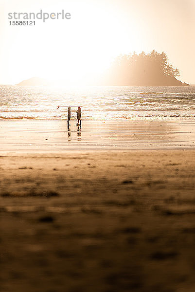 Silhouettenansicht von zwei Surfern am Strand bei Sonnenuntergang  Tofino  Vancouver Island  Kanada