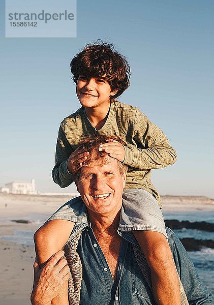 Vater reitet Sohn huckepack am Strand