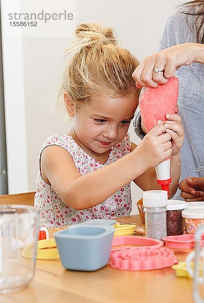 Mutter und Tochter dekorieren Cupcake mit Zuckerguss in der Küche