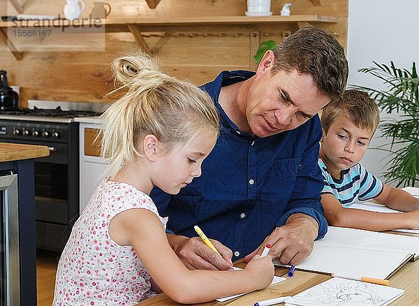Vater hilft Kindern zu Hause bei den Hausaufgaben