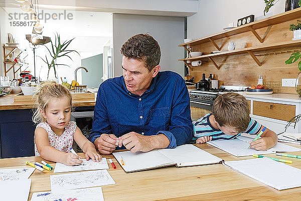 Vater hilft Kindern zu Hause bei den Hausaufgaben