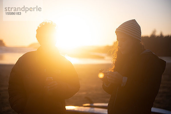 Zwei Freundinnen im mittleren Erwachsenenalter an der Küste bei Sonnenuntergang  Tofino  Vancouver Island  Kanada