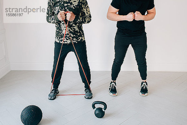 Fitnesstrainer unterrichtet Mann mit Widerstandsband im Studio