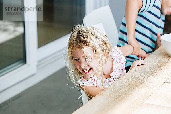 Junge zieht der Schwester am Esstisch spielerisch an der Hand