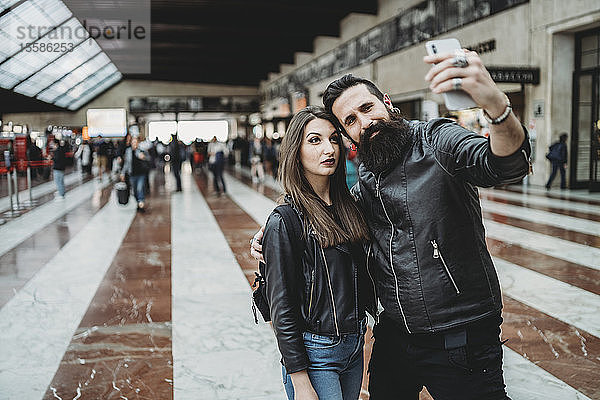 Paar  das sich mit einem Smartphone am Bahnhof selbstständig macht