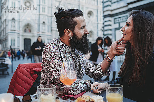 Mann berührt zärtlich das Kinn einer Frau im Café  Santa Maria del Fiore  Florenz  Toskana  Italien