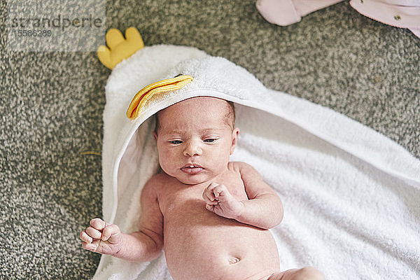 Baby liegt zu Hause auf einem Handtuch mit Kapuze