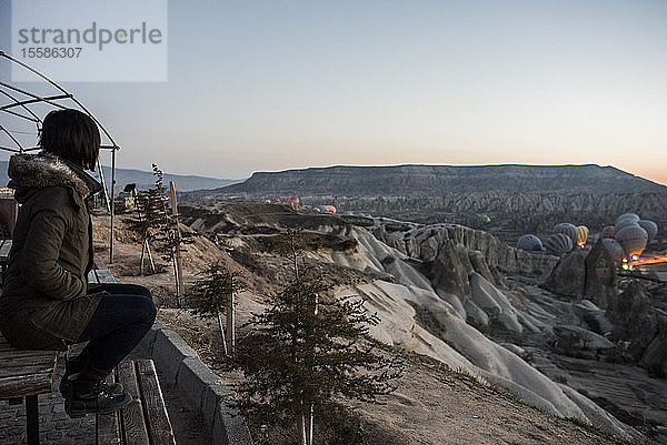 Frau geniesst Ansicht und Darstellung von Heissluftballons im Tal  GÃ¶reme  Kappadokien  Nevsehir  TÃ?rkei