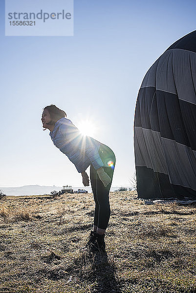 Frau beugt sich gegen das Sonnenlicht vor  Heissluftballon im Hintergrund  GÃ¶reme  Kappadokien  Nevsehir  TÃ?rkei