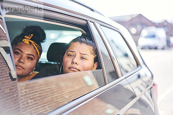 Zwei Teenager-Mädchen auf dem Rücksitz eines Autos  die aus dem Autofenster schauen
