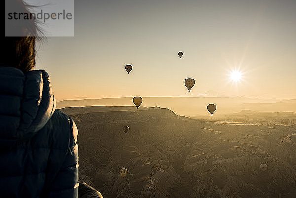 Frau geniesst Aussicht  Heissluftballons fliegen im Hintergrund  GÃ¶reme  Kappadokien  Nevsehir  TÃ?rkei