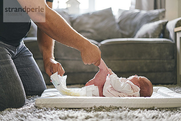 Vater wechselt die Windel des Babys zu Hause