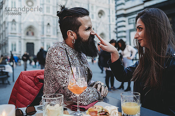 Frau klopft spielerisch auf die Nase eines Mannes im Café  Santa Maria del Fiore  Florenz  Toskana  Italien