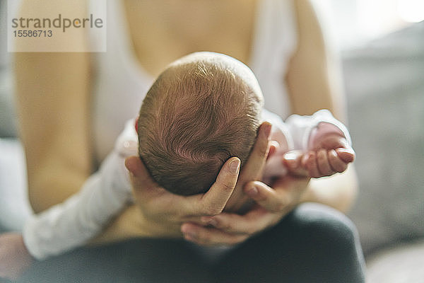 Mutter unterstützt Kopf des Babys auf dem Schoß