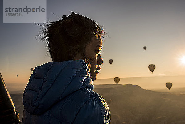 Frau geniesst Aussicht  Heissluftballons fliegen im Hintergrund  GÃ¶reme  Kappadokien  Nevsehir  TÃ?rkei