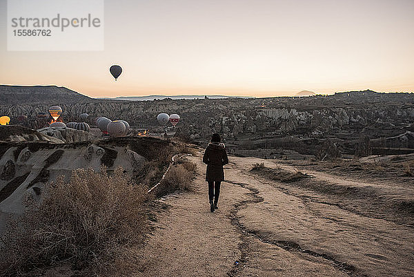 Frau geniesst Ansicht und Darstellung von Heissluftballons im Tal  GÃ¶reme  Kappadokien  Nevsehir  TÃ?rkei