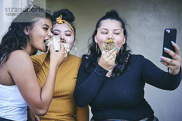 Junge Frau und jugendliche Schwestern posieren für Selbstgefälligkeit beim Kuchenessen