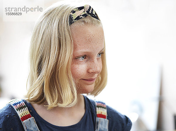 Mädchen mit Sommersprossen und blondem gebauschtem Haar  wegblickend  Kopf und Schulterporträt