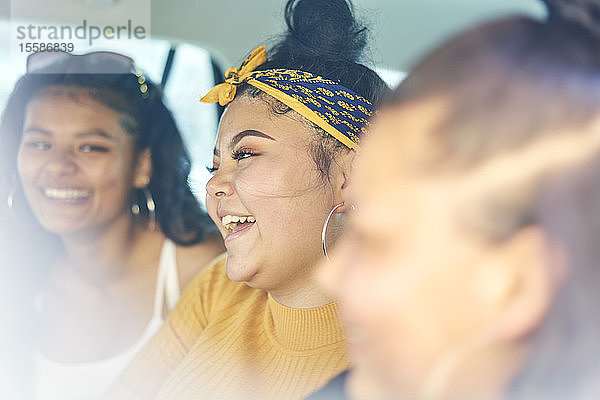 Junge Frau mit jugendlichen Schwestern auf dem Rücksitz im Auto lachend  Nahaufnahme