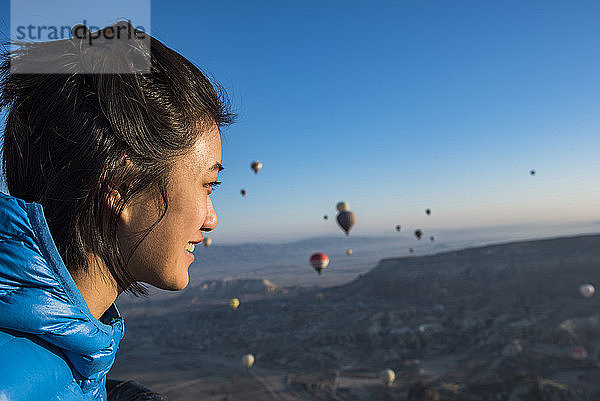 Frau geniesst Aussicht  Heissluftballons fliegen im Hintergrund  GÃ¶reme  Kappadokien  Nevsehir  TÃ?rkei