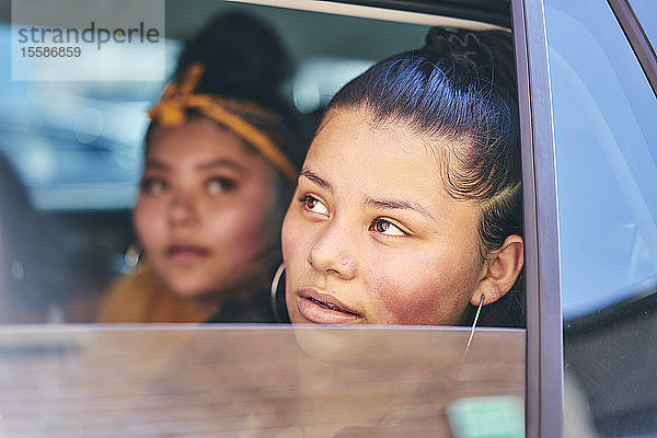 Zwei Teenager-Mädchen auf dem Rücksitz eines Autos  die aus dem Autofenster schauen  Nahaufnahme