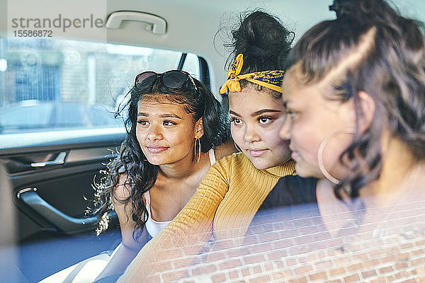 Junge Frau und jugendliche Schwestern auf dem Rücksitz eines Autos