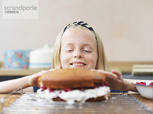 Mädchen backt einen Kuchen  drückt Kuchenteig am Küchentisch