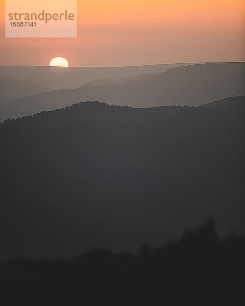 Ein schöner Sonnenuntergang  bei dem die Sonne gerade hinter den Hügeln im Peak District National Park  Derbyshire  England  Vereinigtes Königreich  untergeht.