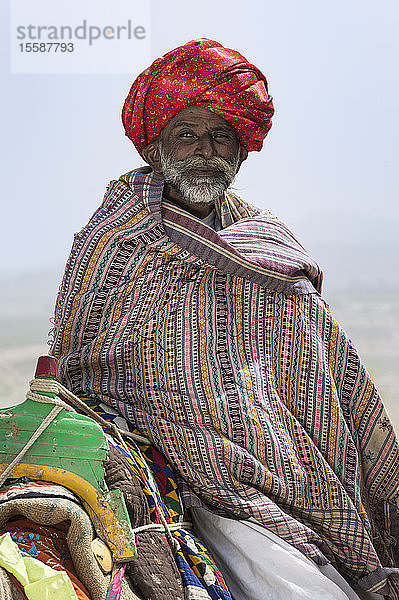 Mann der Dhebariya-Rabari-Gemeinschaft in traditioneller Kleidung mit einem Dromedar  Great Rann of Kutch Desert  Gujarat  Indien