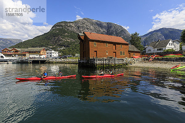 Seekajakfahrer fahren los  schönes Dorf am Eidfjord  Berge und Strand  sonniger Tag  Norwegische Westfjorde  Norwegen  Skandinavien