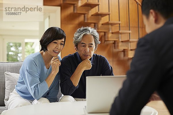 Älteres japanisches Paar zu Hause mit Verkäufer