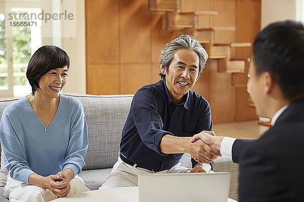 Älteres japanisches Paar zu Hause mit Verkäufer