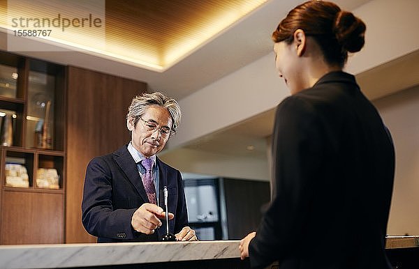 Älterer Geschäftsmann beim Einchecken im Hotel