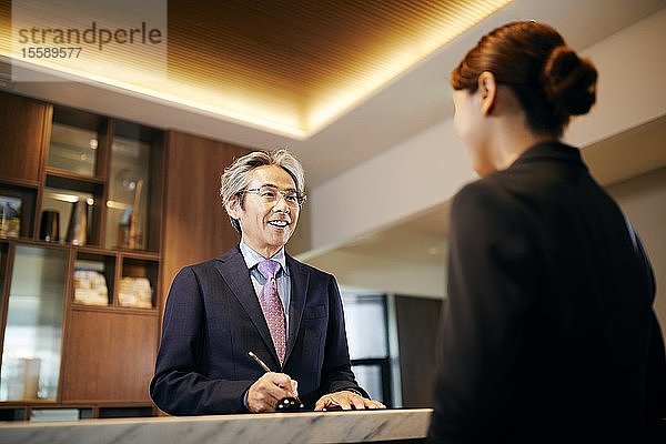 Älterer Geschäftsmann beim Einchecken im Hotel