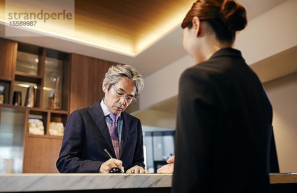 Älterer Geschäftsmann beim Einchecken im Hotel