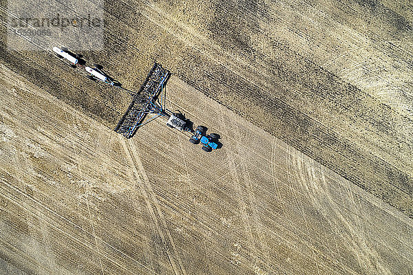 Luftaufnahme einer Einzelkornsämaschine auf einem Feld mit weißen Ammoniaktanks  in der Nähe von Beiseker; Alberta  Kanada