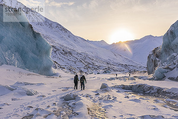 Winterwanderer erkunden den Black Rapids Glacier  während die Sonne über der Alaska Range untergeht; Alaska  Vereinigte Staaten von Amerika