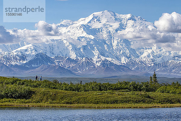 Der Berg Denali im Denali National Park and Preserve  von der Park Road aus gesehen  die zum Wonder Lake führt. Das Foto zeigt Wanderer hinter dem Reflection Pond und im Schatten des Denali; Alaska  Vereinigte Staaten von Amerika