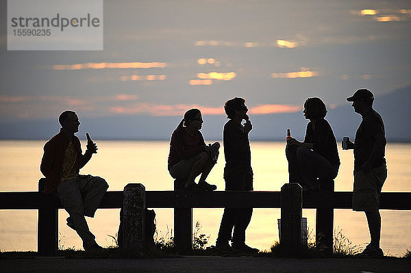Eine Gruppe von Freunden beobachtet gemeinsam den Sonnenuntergang am Point Woronzof in Anchorage  Southcentral Alaska  Sommer/N