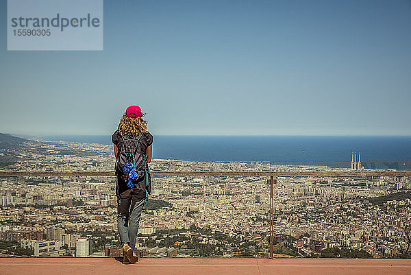 Tourist steht an einem Geländer im Tibidabo-Vergnügungspark mit Blick auf die Stadt Barcelona und das Mittelmeer; Barcelona  Katalonien  Spanien