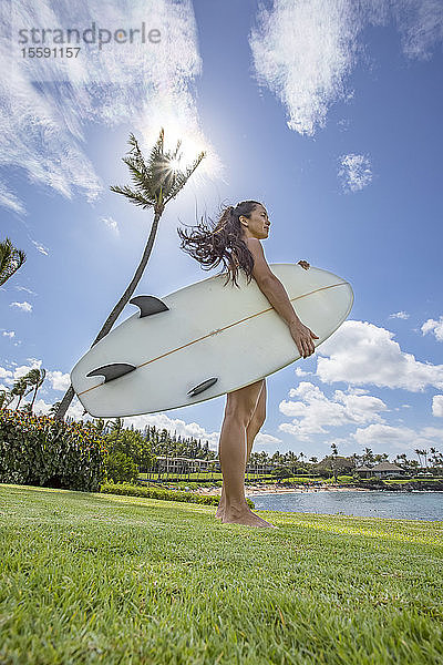 Eine junge Frau mit Surfbrett in der Kapalua Bay und am Strand; Maui  Hawaii  Vereinigte Staaten von Amerika