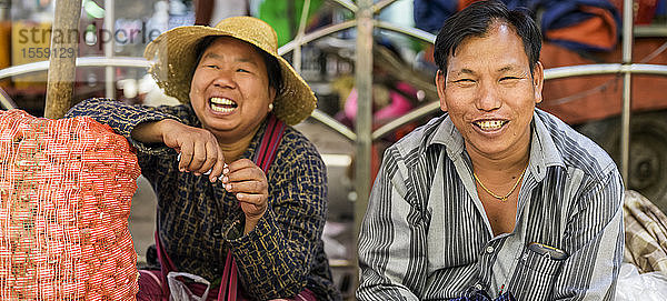 Mann und Frau sitzen lachend auf dem Markt; Taungyii  Staat Shan  Myanmar