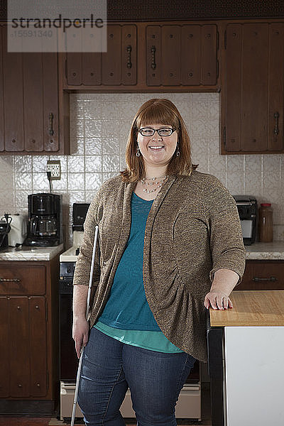 Porträt einer blinden Frau mit ihrem Blindenstock in ihrer Küche