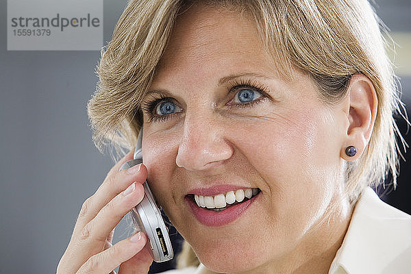 Eine lächelnde Geschäftsfrau  die ein Mobiltelefon benutzt.