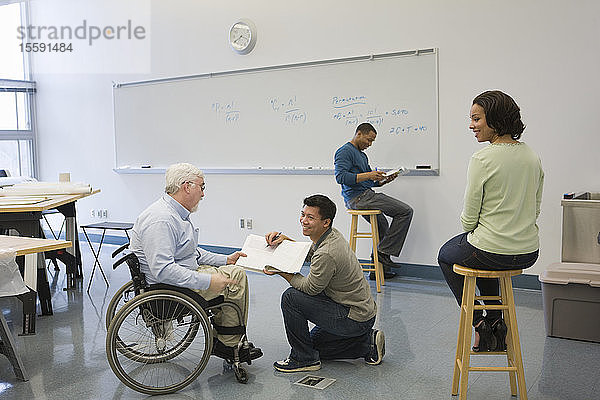 Universitätsprofessor mit Muskeldystrophie mit seinen Studenten in einem Klassenzimmer