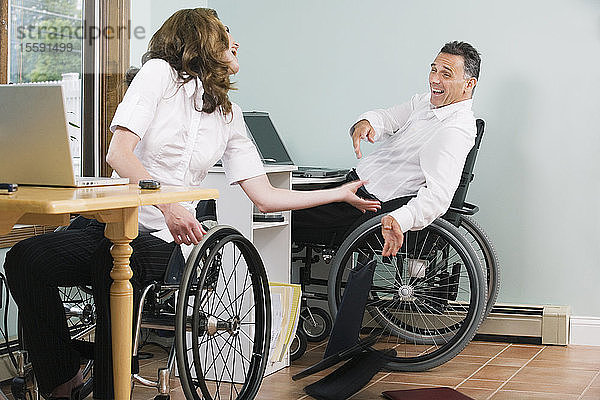 Ein erwachsenes Paar mit Rückenmarksverletzungen sitzt im Rollstuhl und lacht